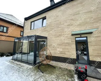 Стеклянная пристройка к дому с безрамным остеклением