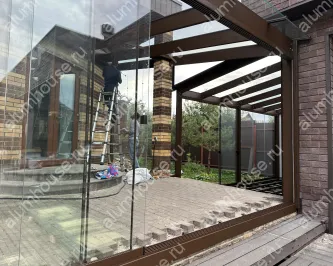 Стеклянная веранда к дому с раздвижным безрамным остеклением