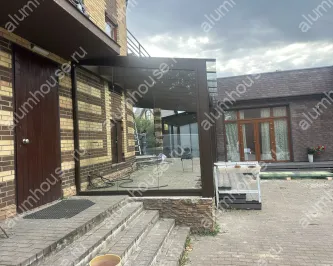 Стеклянная веранда к дому с раздвижным безрамным остеклением