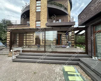 Стеклянная веранда к дому с раздвижным безрамным остеклением