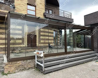 Стеклянная веранда к дому с раздвижным безрамным остеклением