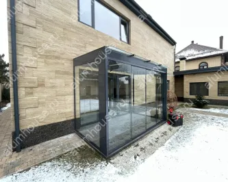Стеклянная пристройка к дому с безрамным остеклением
