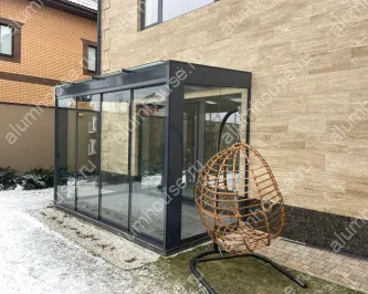Стеклянная пристройка к дому с безрамным остеклением