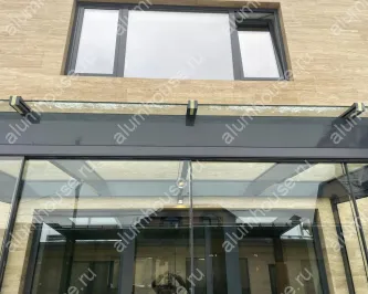 Стеклянная пристройка к дому с безрамным остеклением