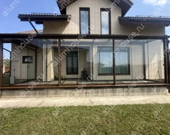 Веранда к дому со стеклянной крышей и безрамным остеклением