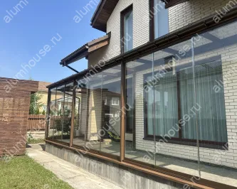 Веранда к дому со стеклянной крышей и безрамным остеклением