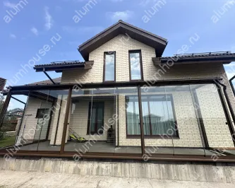 Веранда к дому со стеклянной крышей и безрамным остеклением