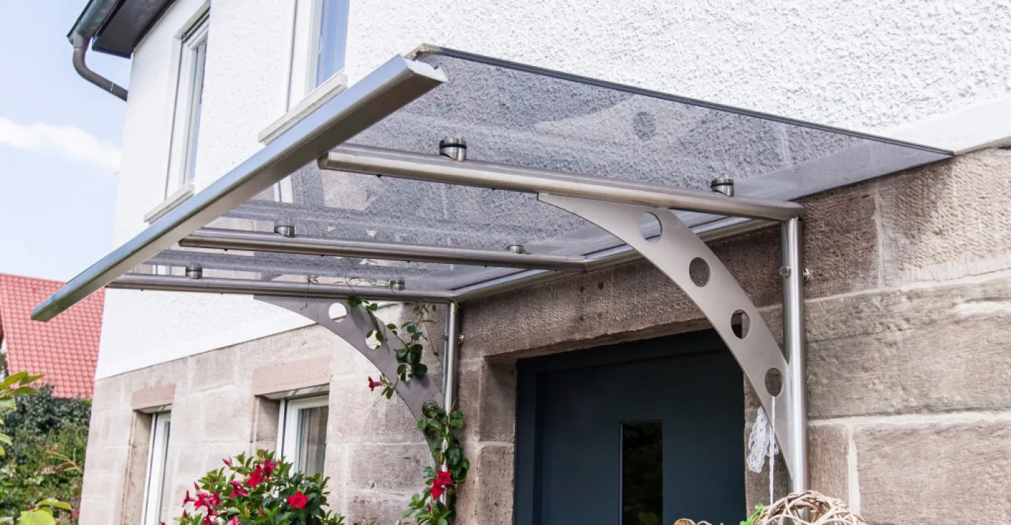 С козырьком из стекла коттедж выглядит актуально и стильно при любой погоде.